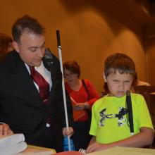 a young blind boy talking to NFB president Mark Riccobonno.