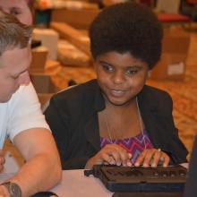 a young woman uses a braille notetaker device.