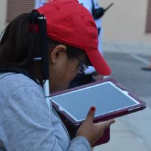 a girl holding her cane looking at an iPad.